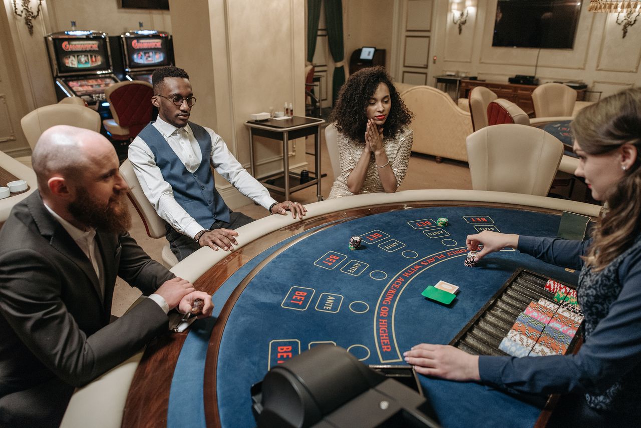 Players engage in a casino card game at an elegant gaming table inside a luxurious venue.